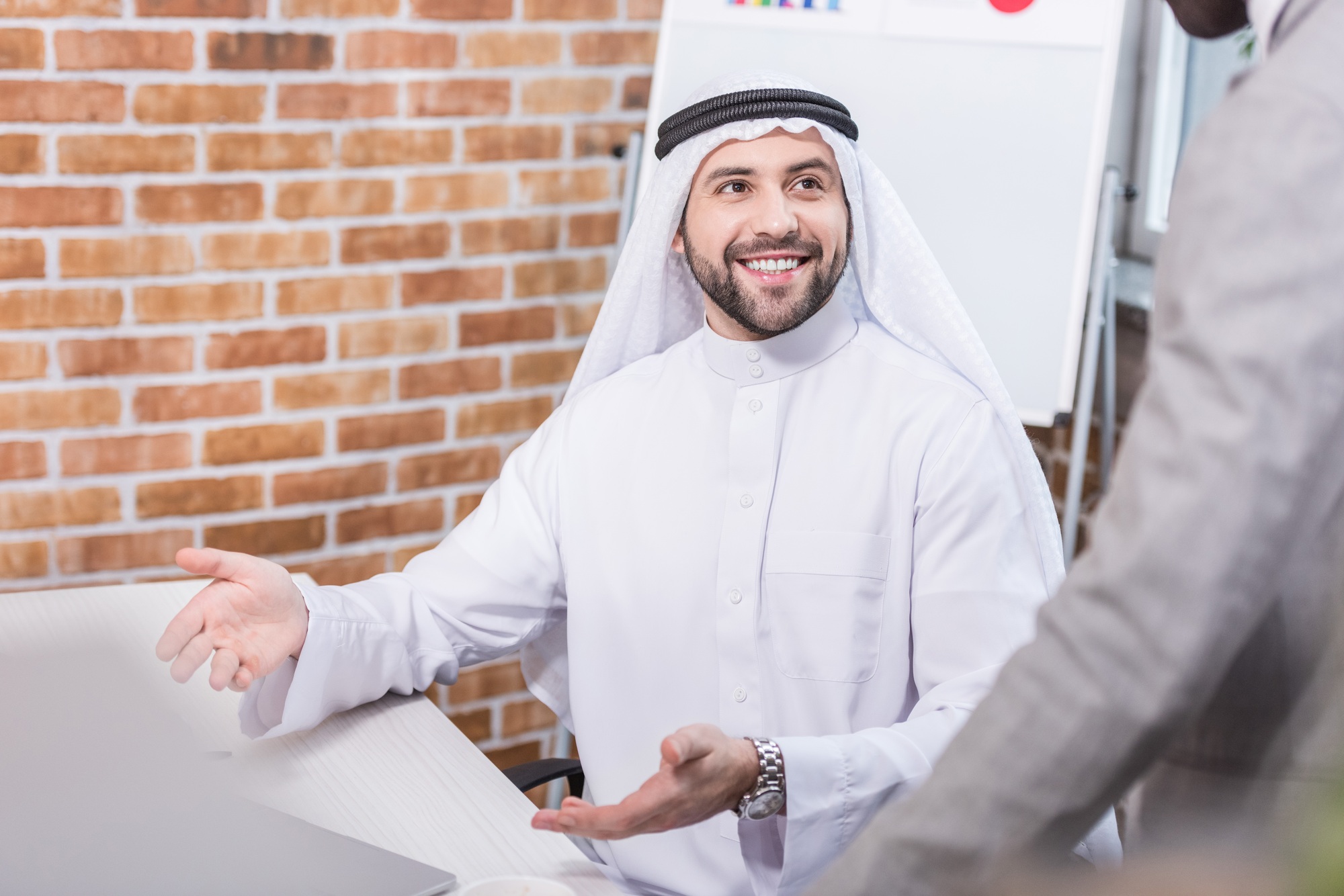 Arabian businessman smiling and gesturing in office